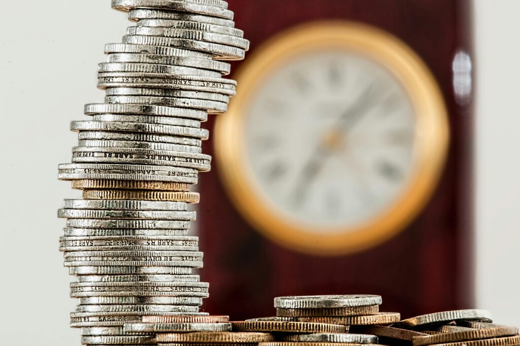coins-currency-investment-insurance-128867-128867 A close-up image of stacked coins with a blurred clock, symbolizing time and money relationship.